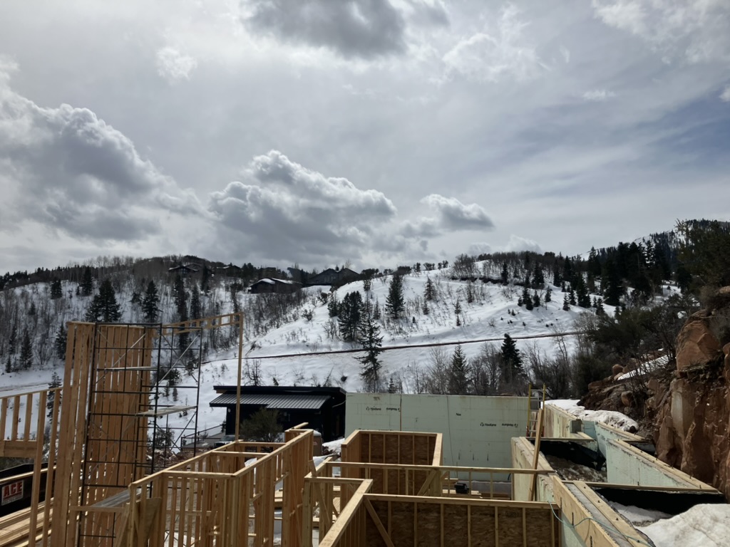 New house under construction in an open area with exposed wooden framing and structural beams by BBA Construction in Utah